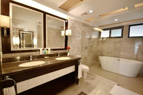 a bathroom with two sinks and a tub and a toilet at Henann Resort Alona Beach in Panglao