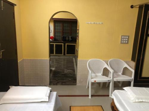 two white chairs in a room with two beds at Kodali Homestays in Bhadrāchalam