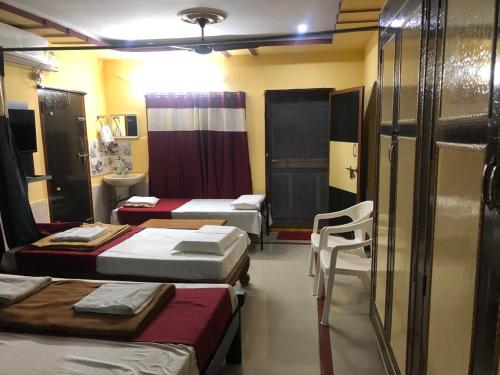 a room with three beds and a chair in it at Kodali Homestays in Bhadrāchalam