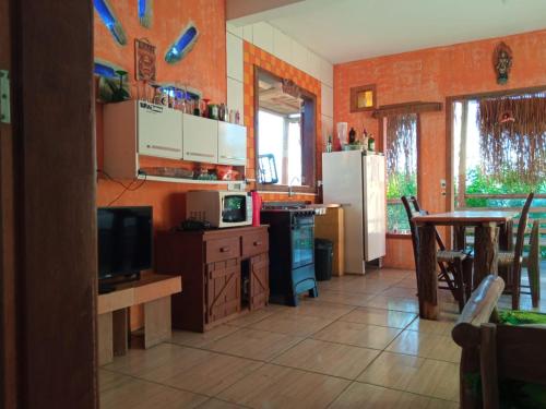 a kitchen with a table and a tv in a room at Sunset Lagoon Praia do Rosa in Praia do Rosa