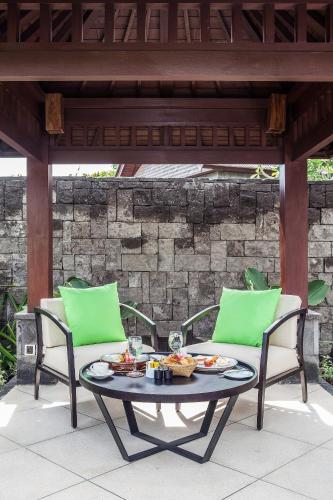 a patio with two chairs and a table with food on it at Sanctoo Suites & Villas in Gianyar