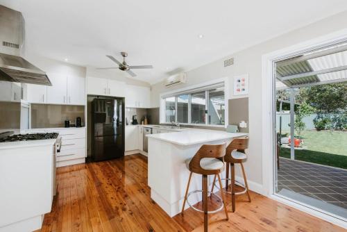 a kitchen with white cabinets and a counter and stools at Georgie's Cottage - The Perfect Mudgee Getaway in Mudgee