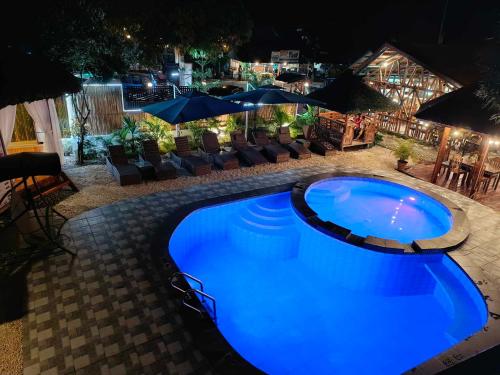a large blue pool with chairs and umbrellas at night at Hotel Oasis Port Barton in San Vicente