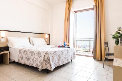 a hotel room with a bed and a large window at Hotel Rondine in Marinella di Sarzana