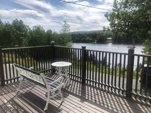 a white bench sitting on a deck with a table at Golden Hour Villa in Peggy's Cove Rd in French Village