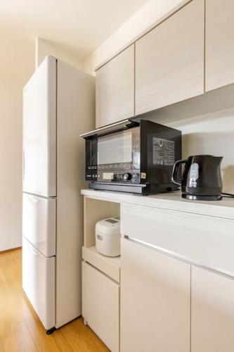 a kitchen with a white refrigerator and a microwave at Jintai House501 in Fukuoka