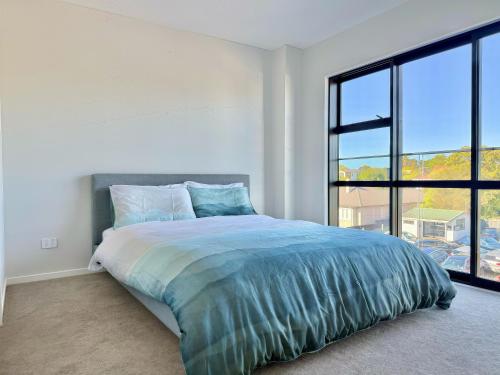 a bedroom with a large bed with a large window at Lake Quarter Apartment in Auckland