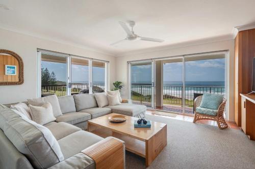 a living room with a couch and a table at Pippi Beach Penthouse - Oceanstays - Pool & Beachfront in Yamba