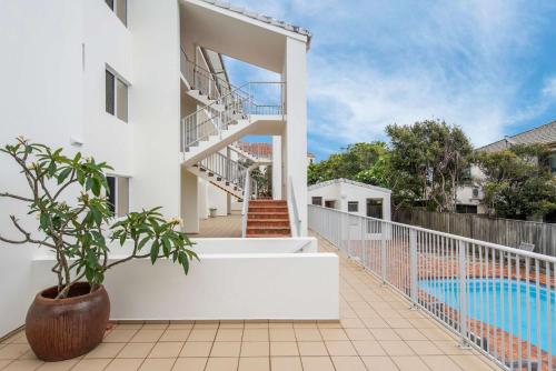 a white house with a staircase and a swimming pool at Pippi Beach Penthouse - Oceanstays - Pool & Beachfront in Yamba