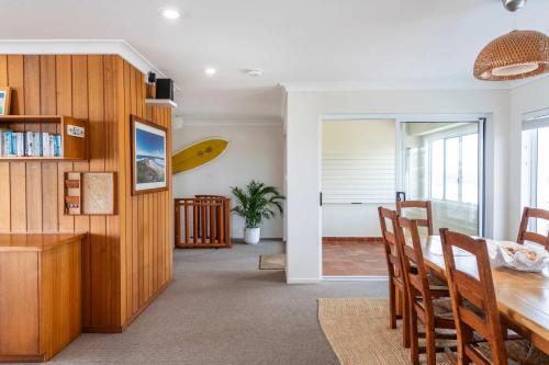 a dining room with a table and a surfboard on the wall at Pippi Beach Penthouse - Oceanstays - Pool & Beachfront in Yamba
