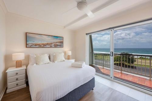 a bedroom with a bed and a large window at Pippi Beach Penthouse - Oceanstays - Pool & Beachfront in Yamba