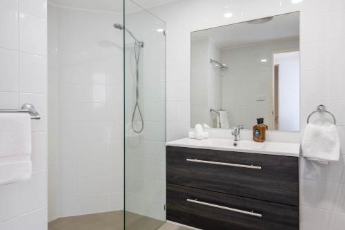 a bathroom with a shower with a sink and a mirror at Pippi Beach Penthouse - Oceanstays - Pool & Beachfront in Yamba