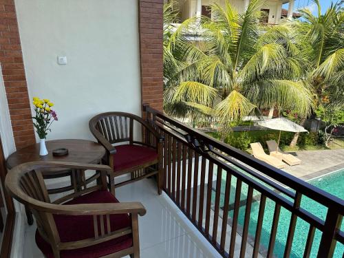 a balcony with two chairs and a table and a palm tree at Brata Cottage Ubud in Ubud