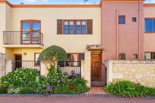 a house with a gate and flowers in front of it at Venice On The Beach Family Waterfront Escape in Wannanup