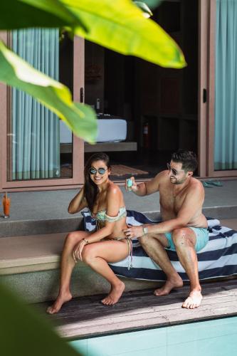 a man and a woman sitting next to a pool at Panorama Villas El Nido in El Nido