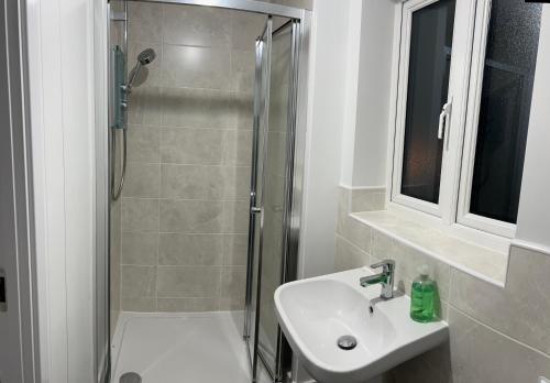 een witte badkamer met douche en wastafel bij Cozie Zone & Brekkie Hucknall, Nottingham in Hucknall