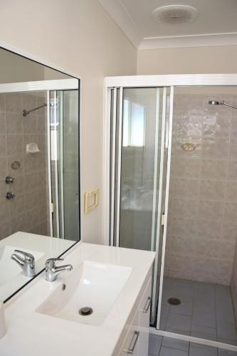 Un baño blanco con lavabo y ducha. en Baybreeze - Bring your own linen, en South West Rocks