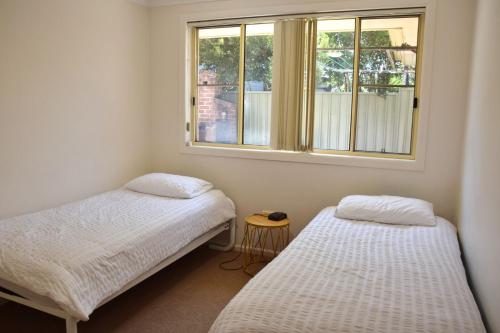 Dos camas en una habitación con ventana. en Baybreeze - Bring your own linen, en South West Rocks