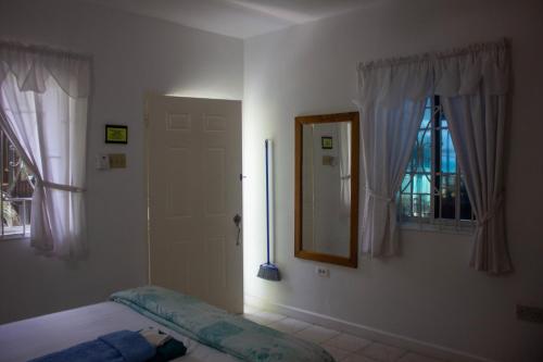 a bedroom with a bed and a mirror and window at Mom's Place Negril in Negril