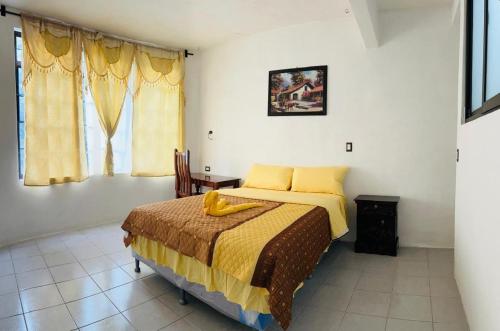 a bedroom with a bed with yellow sheets and a window at Hotel Luna in San Marcos La Laguna