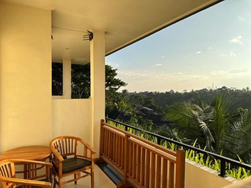 a balcony with chairs and a table and a view at Brata Cottage Ubud in Ubud