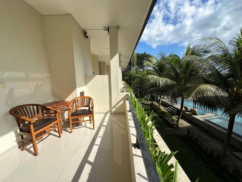 a balcony with a table and chairs and the ocean at Brata Cottage Ubud in Ubud