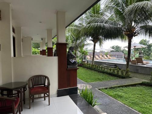 a patio with a table and chairs and palm trees at Brata Cottage Ubud in Ubud