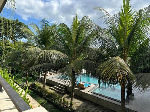 a swimming pool with palm trees in a resort at Brata Cottage Ubud in Ubud