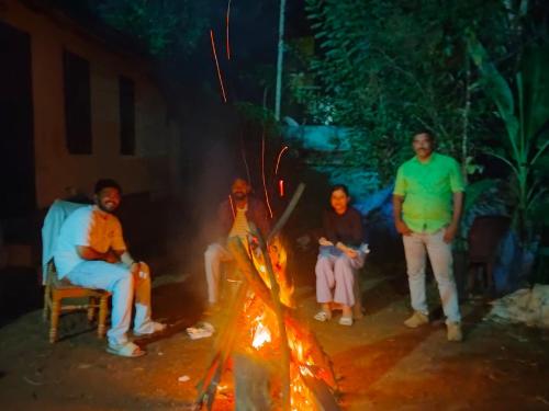 a group of people sitting around a fire at Riya Home Stay Munnar in Anaviratty