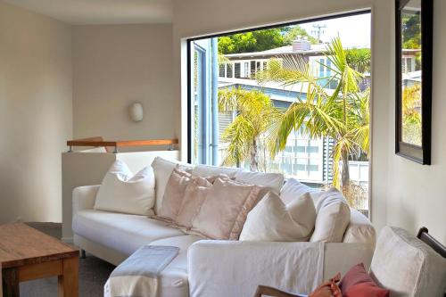 a living room with a white couch and a large window at Casa on Tawa, Oneroa - Be My Guest Waiheke in Oneroa