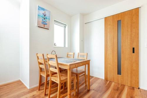 a dining room table with chairs and a wooden door at Chigasaki vacation house in Chigasaki