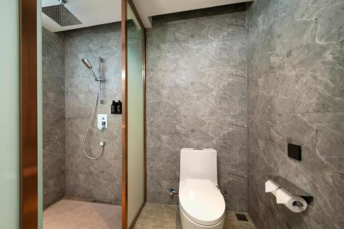 a bathroom with a toilet and a shower at Model J Hotel Jakarta Soekarno - Hatta Airport 曼居酒店 雅加达苏加诺哈达机场店 in Gardu