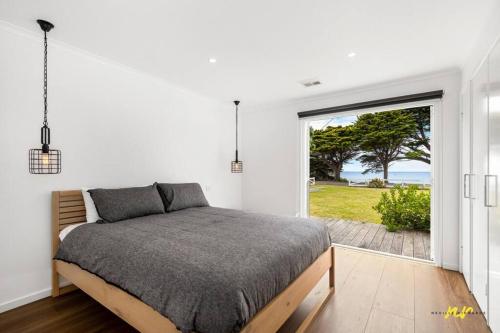 a bedroom with a bed and a large window at The Esplanade Indented Heads- Beach front, Luxury, Sleeps 8, Spacious, Aircon, Heating, in Indented Head