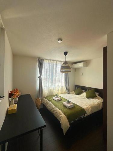 a bedroom with a bed and a table and a window at Osaka KyoSai-A 栖晚 in Osaka