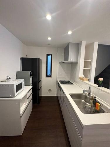a white kitchen with a sink and a microwave at Osaka KyoSai-A 栖晚 in Osaka