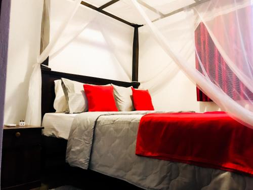 a bedroom with a canopy bed with red pillows at Coastal House in Mirissa