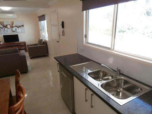 a kitchen with a sink and a living room at Whitsunday Sands Resort in Bowen