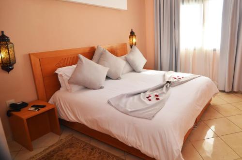 um quarto com uma cama com lençóis brancos e almofadas em Atlantic Palm Beach em Agadir