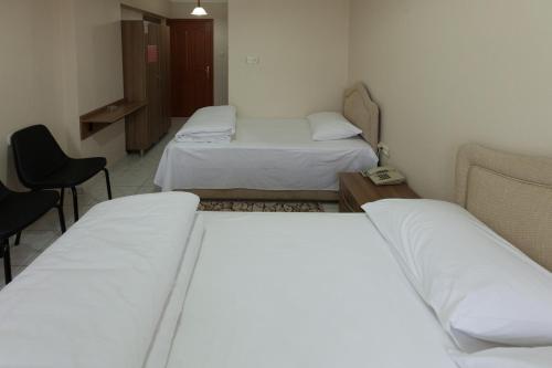 a room with three beds and a table and chairs at Gizem Pansiyon in Canakkale
