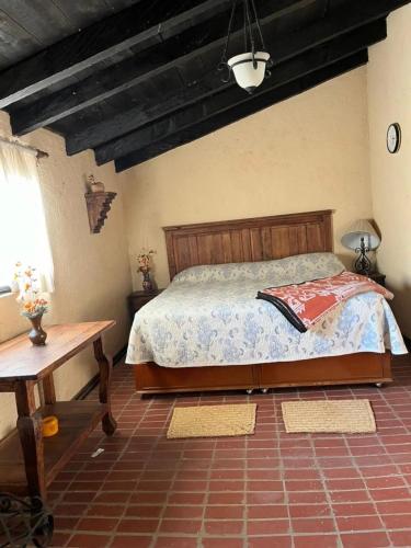 a bedroom with a bed and a wooden table at Cabaña El Tigrito in Quiroga