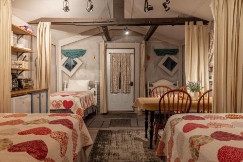 a room with two beds and a table and a door at Auberge Old Chelsea in Chelsea
