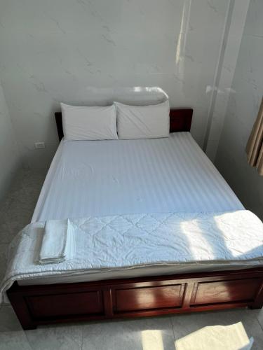 a bed with white sheets and pillows on it at Bảo Di Sóc Trăng Hotel in Soc Trang
