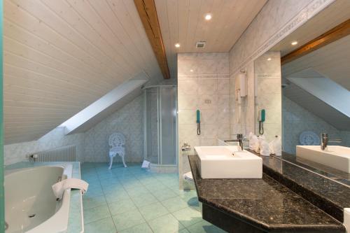 a bathroom with two sinks and a bath tub and a tub at Hotel Landhaus Säntis Herisau in Herisau