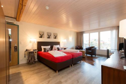 ein Schlafzimmer mit einem großen roten Bett in einem Zimmer in der Unterkunft Hotel Landhaus Säntis Herisau in Herisau