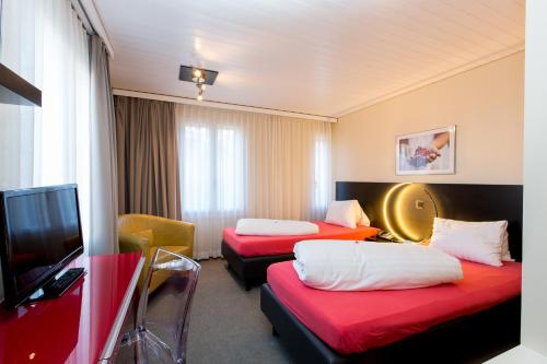 a hotel room with two beds and a flat screen tv at Hotel Landhaus Säntis Herisau in Herisau