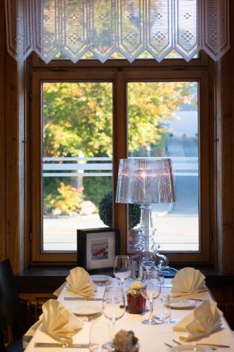a table with glasses and a lamp in front of a window at Hotel Landhaus Säntis Herisau in Herisau