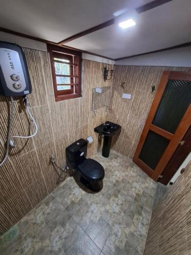 a bathroom with a toilet in a room with a television at Dambullawatha Bungalow Garden Villa in Hikkaduwa