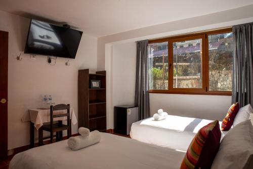 a bedroom with two beds and a tv on the wall at Susanna Inn Machupicchu in Machu Picchu