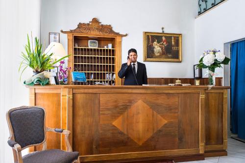 a man in a suit talking on a phone behind a desk at Grande Albergo Quattro Stagioni in Rieti