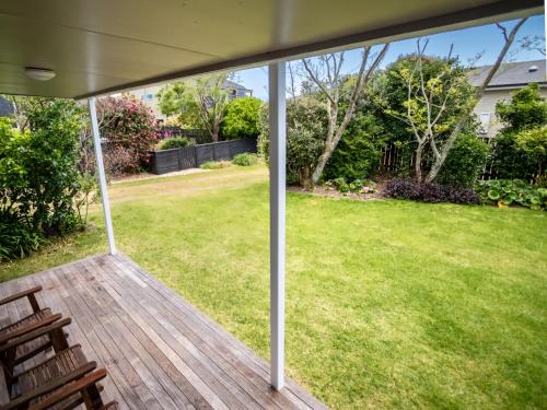 a screened porch with a view of a yard at At The Beach - Pohara Holiday Home in Takaka